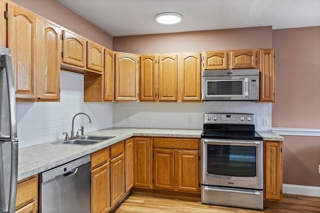 kitchen with a sink, light wood finished floors, appliances with stainless steel finishes, and light countertops