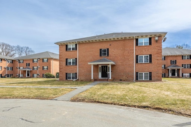 exterior space with brick siding and a front lawn