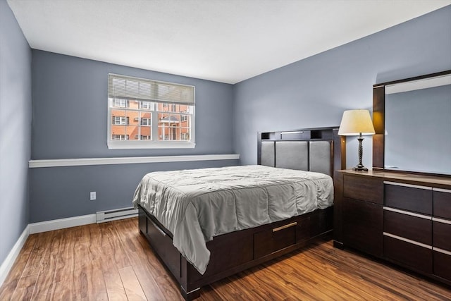 bedroom featuring wood finished floors, baseboards, and a baseboard radiator