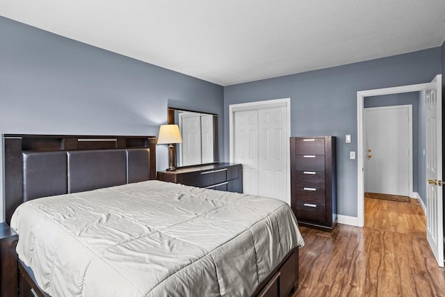 bedroom with a closet, baseboards, and wood finished floors