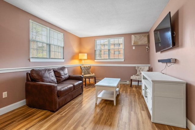 living area with light wood-type flooring, baseboards, and a healthy amount of sunlight