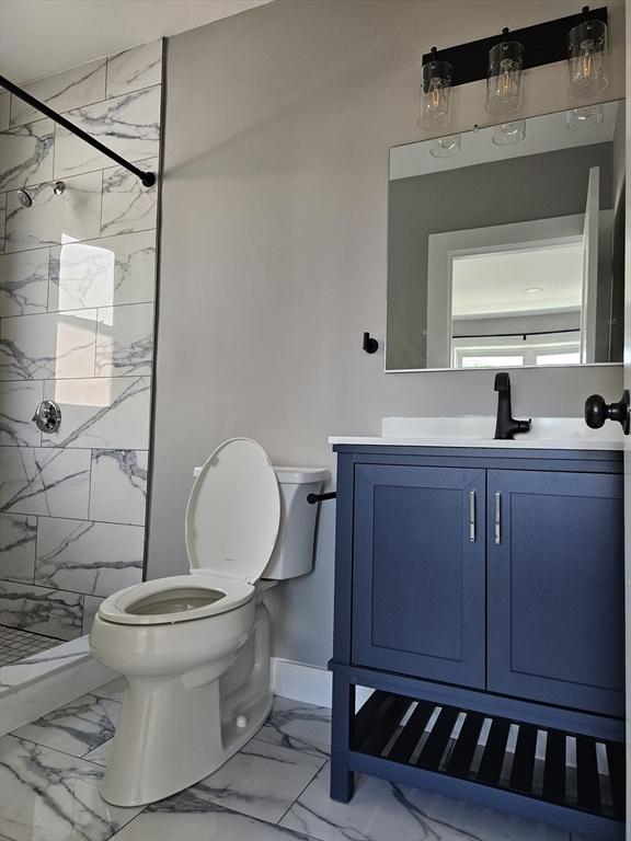 bathroom with vanity, toilet, and a tile shower