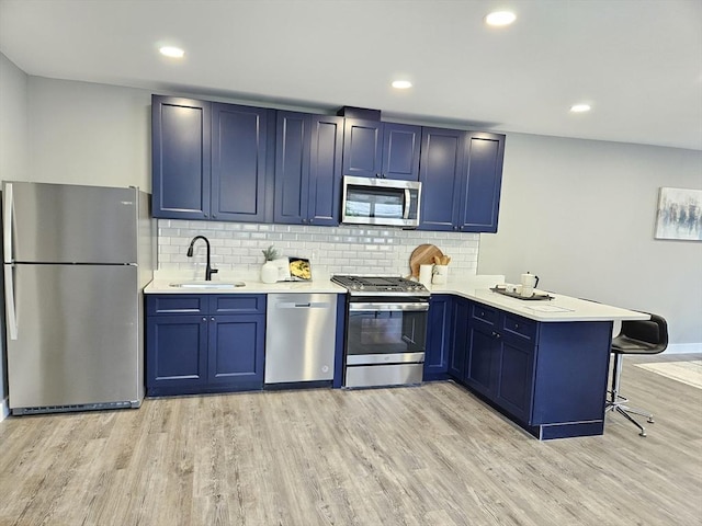 kitchen featuring sink, a breakfast bar area, blue cabinetry, appliances with stainless steel finishes, and kitchen peninsula