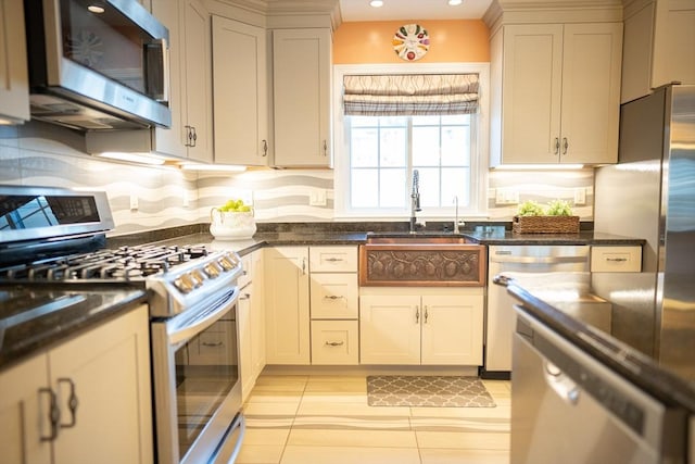 kitchen with a sink, dark stone countertops, backsplash, recessed lighting, and stainless steel appliances