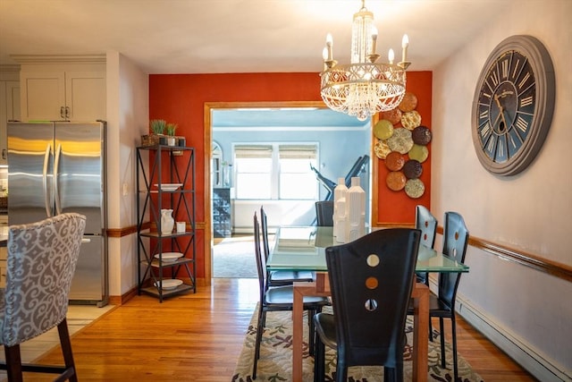 dining area with a baseboard heating unit, an inviting chandelier, light wood-style floors, and baseboards