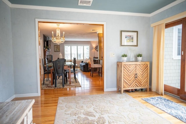 entrance foyer featuring visible vents, baseboards, light wood-style floors, and ornamental molding