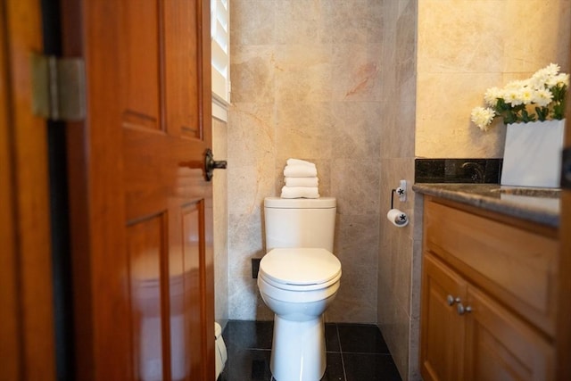 bathroom with toilet, tile walls, vanity, and tile patterned flooring