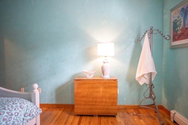 bedroom with wood finished floors, baseboards, and a baseboard radiator