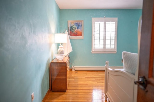 bedroom with a baseboard radiator, baseboards, and light wood-style flooring