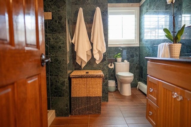 bathroom featuring toilet, a baseboard heating unit, tile walls, tile patterned flooring, and vanity