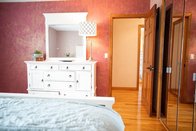 bedroom with wallpapered walls, baseboards, and light wood-type flooring