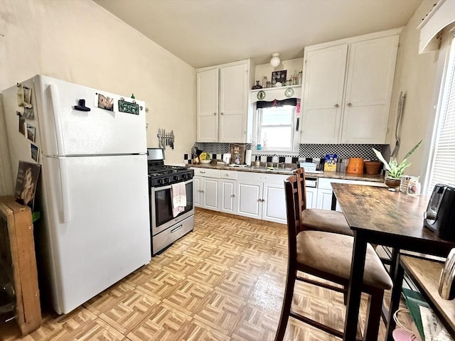 262 Adams St, Newton, MA 02458 - kitchen with gas stove, freestanding refrigerator, white cabinetry, decorative backsplash, and open shelves