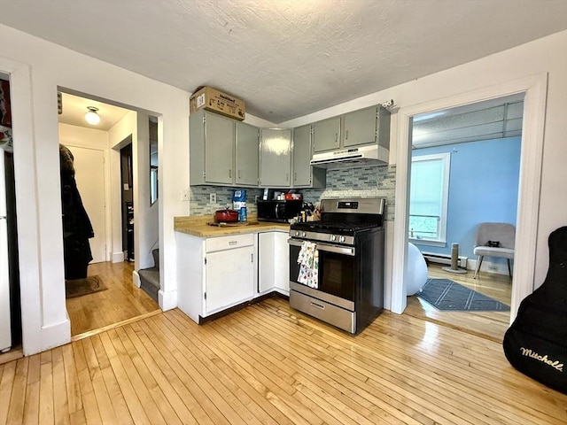 262 Adams St, Newton, MA 02458 - kitchen with stainless steel gas range oven, under cabinet range hood, light countertops, light wood finished floors, and backsplash