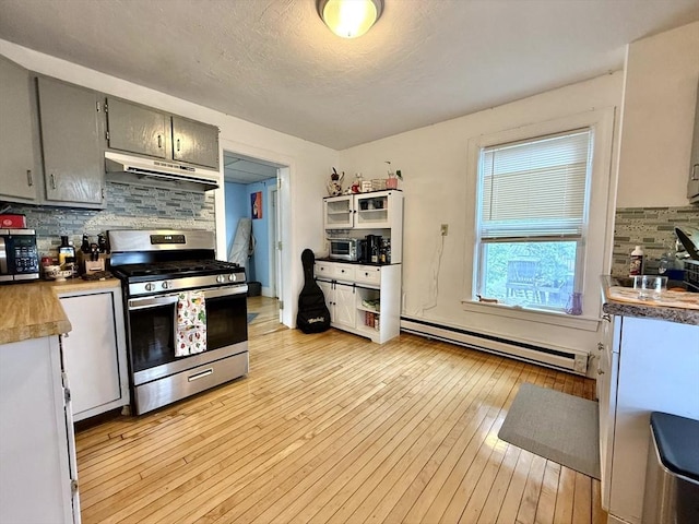 262 Adams St, Newton, MA 02458 - kitchen featuring stainless steel appliances, under cabinet range hood, baseboard heating, tasteful backsplash, and light wood finished floors