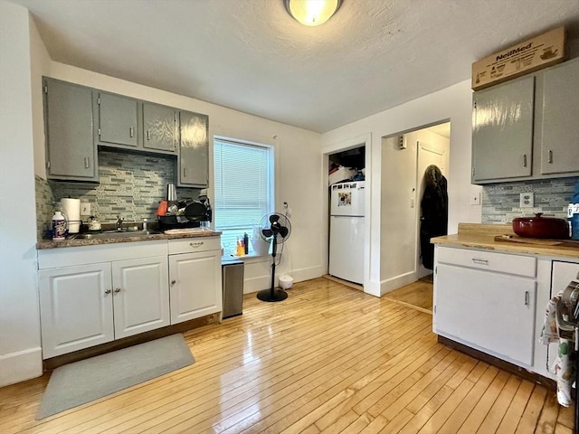 262 Adams St, Newton, MA 02458 - kitchen featuring freestanding refrigerator, tasteful backsplash, light wood finished floors, and gray cabinetry
