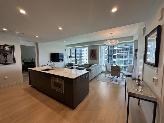 133 Seaport Blvd Unit 1118, Boston, MA 02210 - kitchen featuring light wood-style floors, a chandelier, a center island with sink, plenty of natural light, and recessed lighting