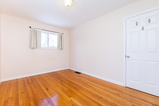 spare room featuring visible vents, light wood-style flooring, and baseboards