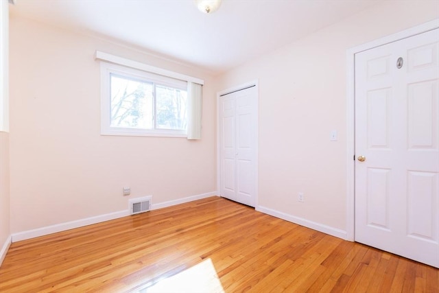 unfurnished bedroom with baseboards, a closet, visible vents, and light wood-style floors