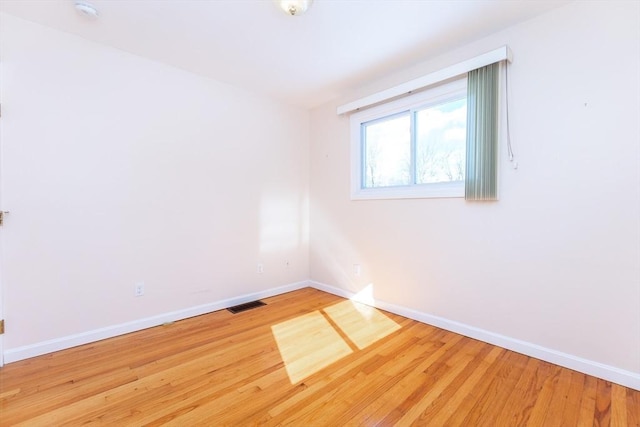 unfurnished room featuring visible vents, baseboards, and wood finished floors