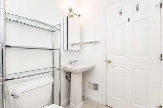 bathroom with baseboards, visible vents, toilet, tile patterned floors, and a sink