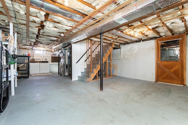 below grade area featuring independent washer and dryer, stairway, and heating unit