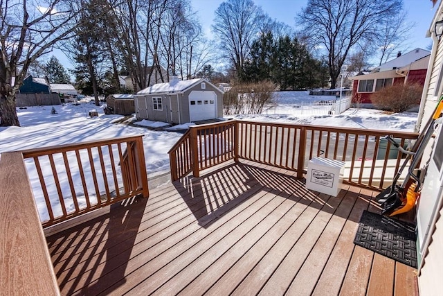 snow covered deck featuring an outdoor structure, a detached garage, and fence