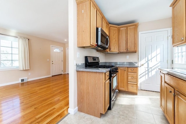 kitchen with stainless steel appliances, a wealth of natural light, visible vents, and baseboards