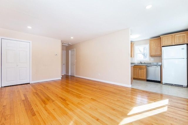 unfurnished living room featuring light wood finished floors, recessed lighting, a sink, and baseboards