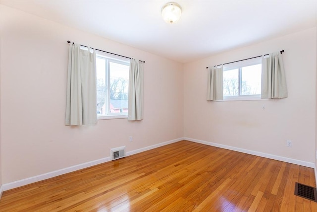 empty room featuring baseboards, visible vents, and light wood-style floors