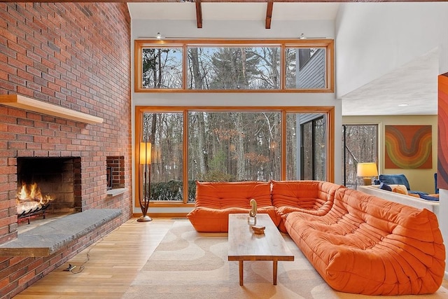 living room featuring light hardwood / wood-style flooring, a healthy amount of sunlight, a high ceiling, and a brick fireplace