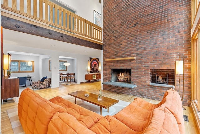 living room featuring hardwood / wood-style floors, a high ceiling, and a brick fireplace