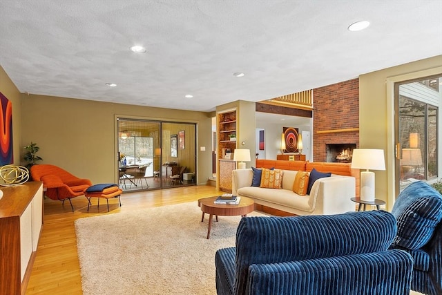 living room with a brick fireplace, plenty of natural light, and light hardwood / wood-style flooring