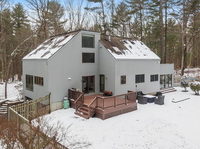 snow covered back of property with a wooden deck