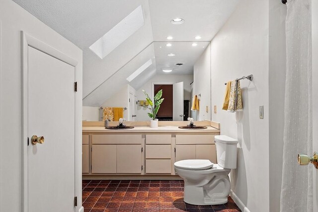 bathroom featuring vanity, toilet, and lofted ceiling with skylight