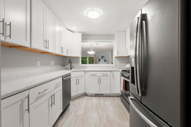 20 Hawthorne Vlg Unit C, Franklin, MA 02038 - kitchen featuring appliances with stainless steel finishes, white cabinets, light wood-style flooring, and a textured ceiling