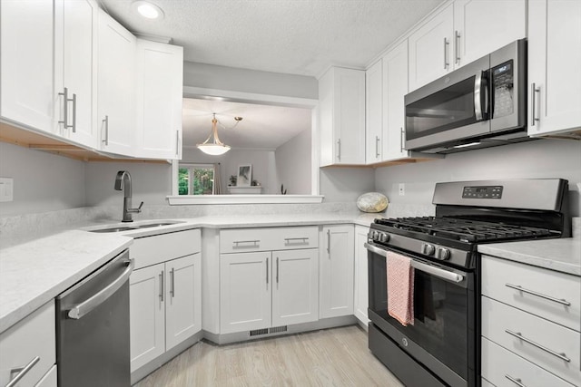 20 Hawthorne Vlg Unit C, Franklin, MA 02038 - kitchen with stainless steel appliances, light countertops, white cabinetry, light wood-type flooring, and a textured ceiling