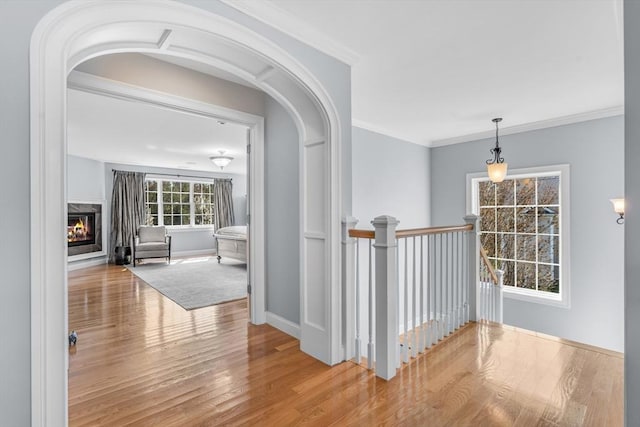 corridor with baseboards, crown molding, wood finished floors, and an upstairs landing