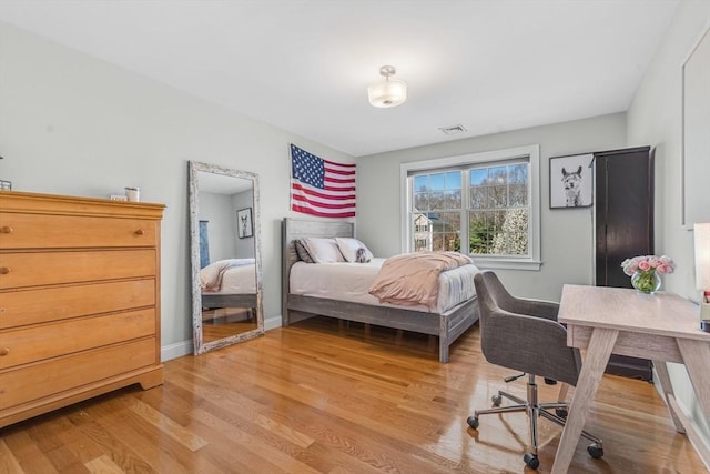 bedroom featuring baseboards, light wood-style flooring, and visible vents