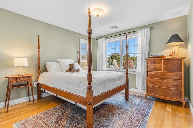 bedroom with visible vents, baseboards, and wood finished floors