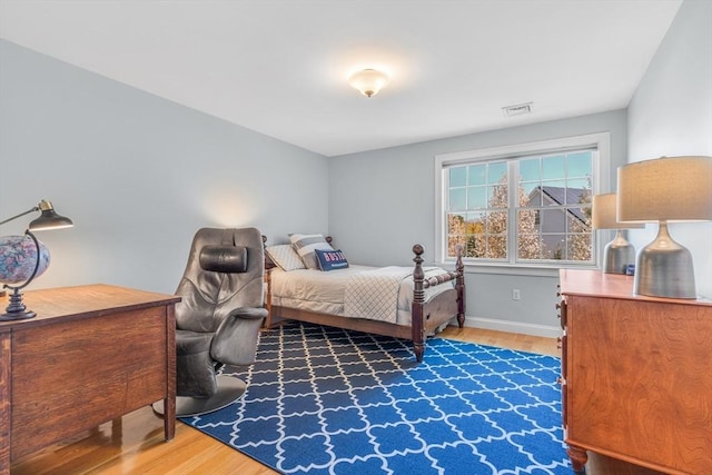 bedroom featuring baseboards, wood finished floors, and visible vents