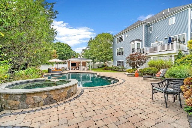 view of swimming pool with fence, a gazebo, a pool with connected hot tub, an outbuilding, and a patio