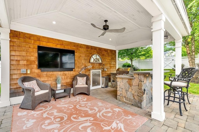 view of patio / terrace with area for grilling, a ceiling fan, fence, outdoor wet bar, and a grill