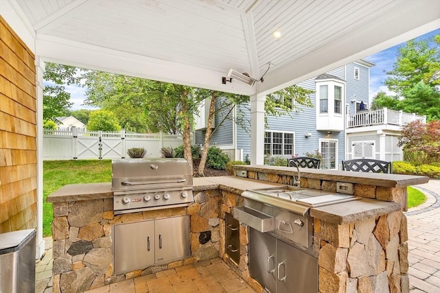 view of patio / terrace with an outdoor kitchen, fence, a gate, and grilling area