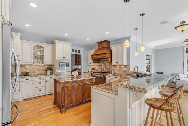kitchen with a sink, light wood-style flooring, stainless steel appliances, a peninsula, and custom range hood