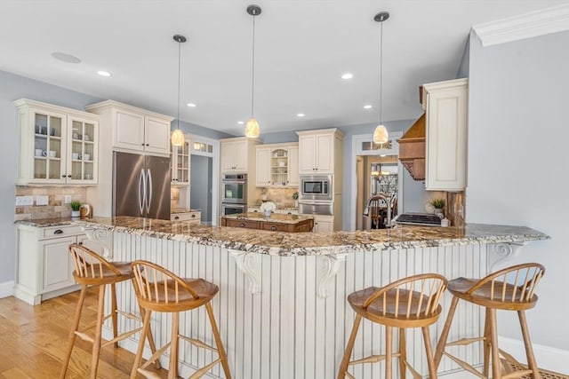 kitchen featuring appliances with stainless steel finishes, tasteful backsplash, light wood finished floors, and a warming drawer