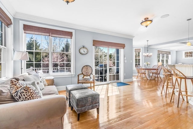 living room with plenty of natural light, ornamental molding, and light wood-style flooring