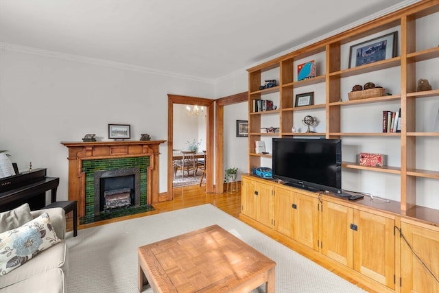 living room with a chandelier, crown molding, a fireplace, and light wood-type flooring