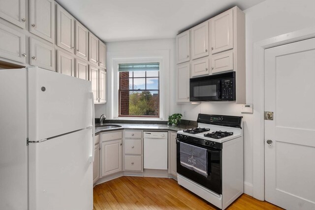 kitchen with light hardwood / wood-style flooring, white cabinetry, sink, and white appliances