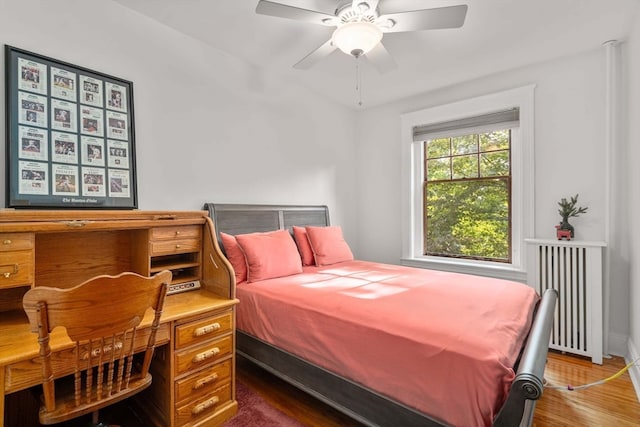 bedroom with ceiling fan, radiator, and dark hardwood / wood-style flooring