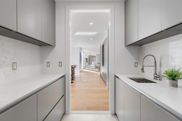 bar with sink, light wood-type flooring, and decorative backsplash